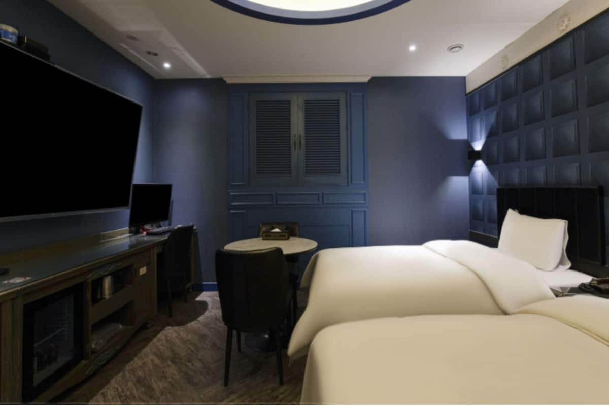Une chambre d’hôtel avec un grand lit, une télévision, une petite table et un coin salon.