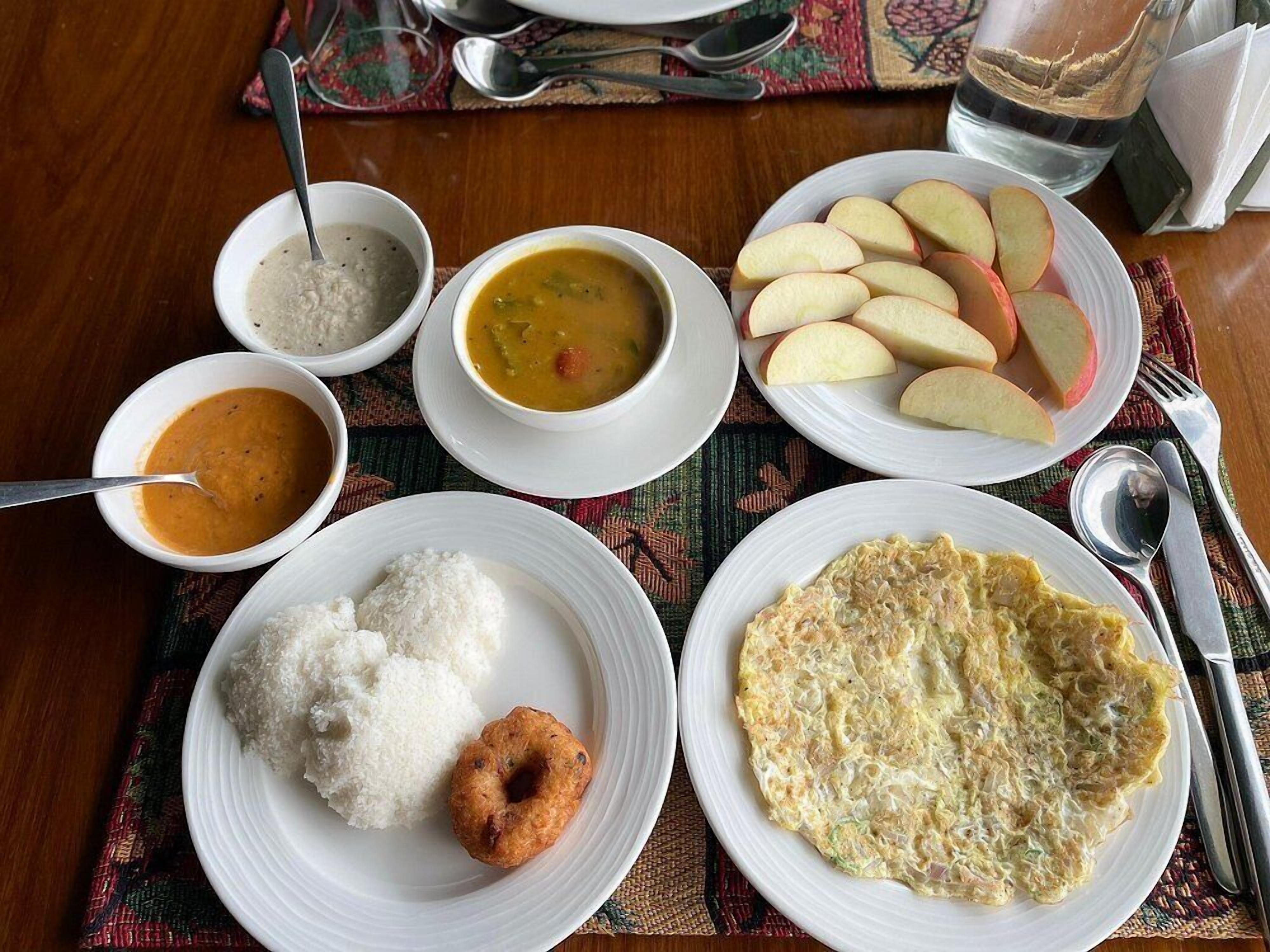 A table with various dishes including rice, soup, and a plate of sliced apples.