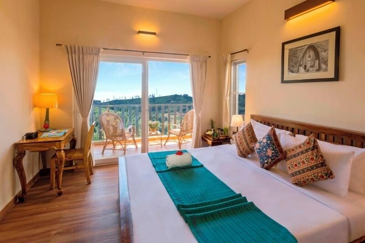 A hotel room with a bed, a desk, a chair, and a balcony with a view.