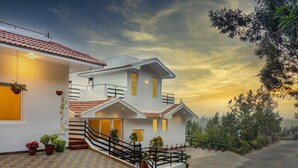 A two-story house with a tiled roof, a staircase, and potted plants. - Sleeping Beauty By Nature Resorts  (Aruvankadu)