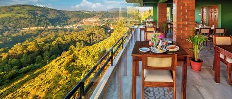 A restaurant with outdoor seating overlooking a mountainous landscape.