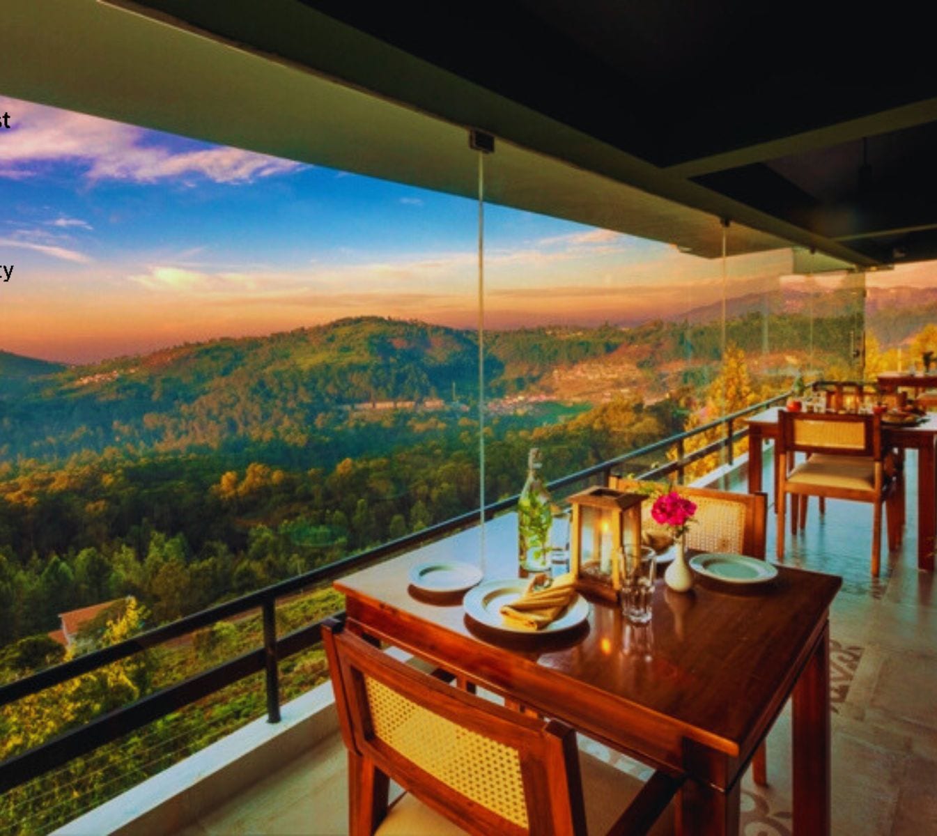 A dining area with a table set for two, overlooking a scenic view of a forested landscape.