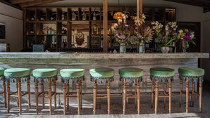 A bar area with wooden stools, a marble counter, and a variety of bottles and decorative items. - Samsara Alaçatı (Çeşme)