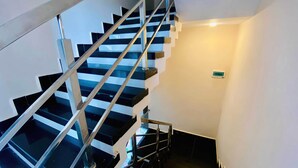 A modern staircase with black and white steps and metal railings, leading to an upper floor. - Hotel Kush Palace (Ujjain)
