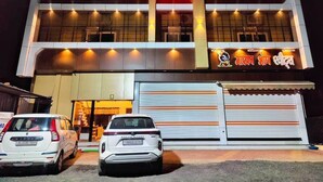 A hotel named KUSH PALACE with a prominent sign, two parked cars, and a closed shuttered entrance. - Hotel Kush Palace (Ujjain)