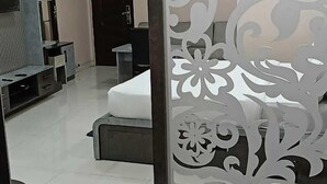 A modern living room with a sofa, TV, and a decorative partition with floral patterns. - HOTEL JD INN (Dumka)