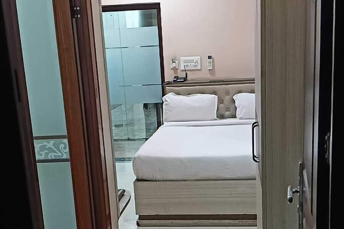 A hotel room with a bed, a wardrobe, and a bathroom visible through an open door.