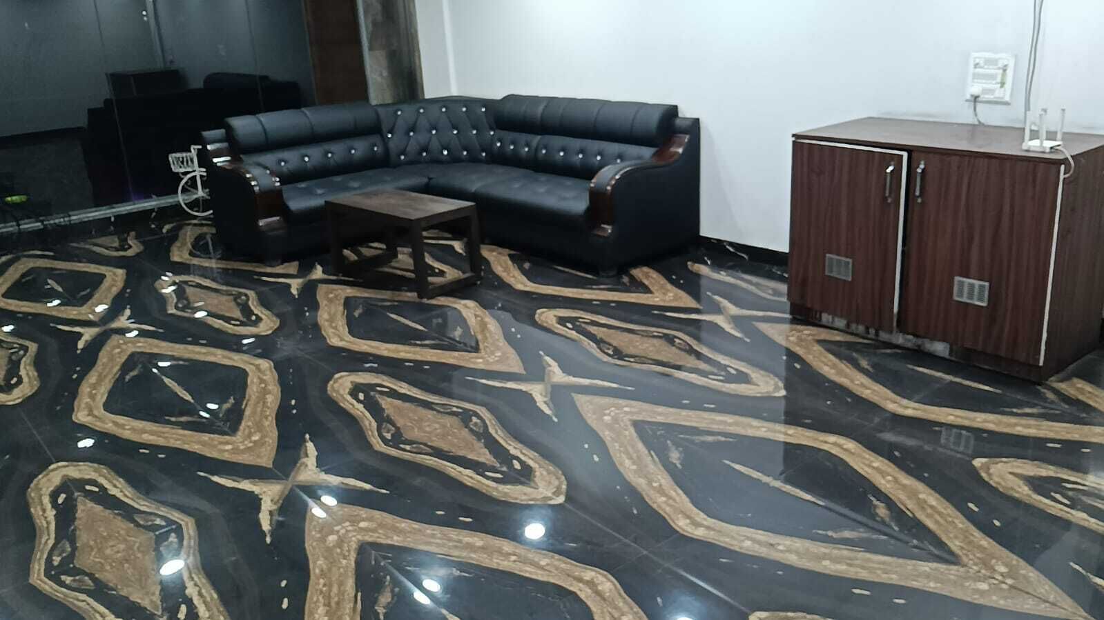 Ein Raum mit einem schwarzen und goldenen Fußboden, einer schwarzen Ledersofa und einem Holzschrank.