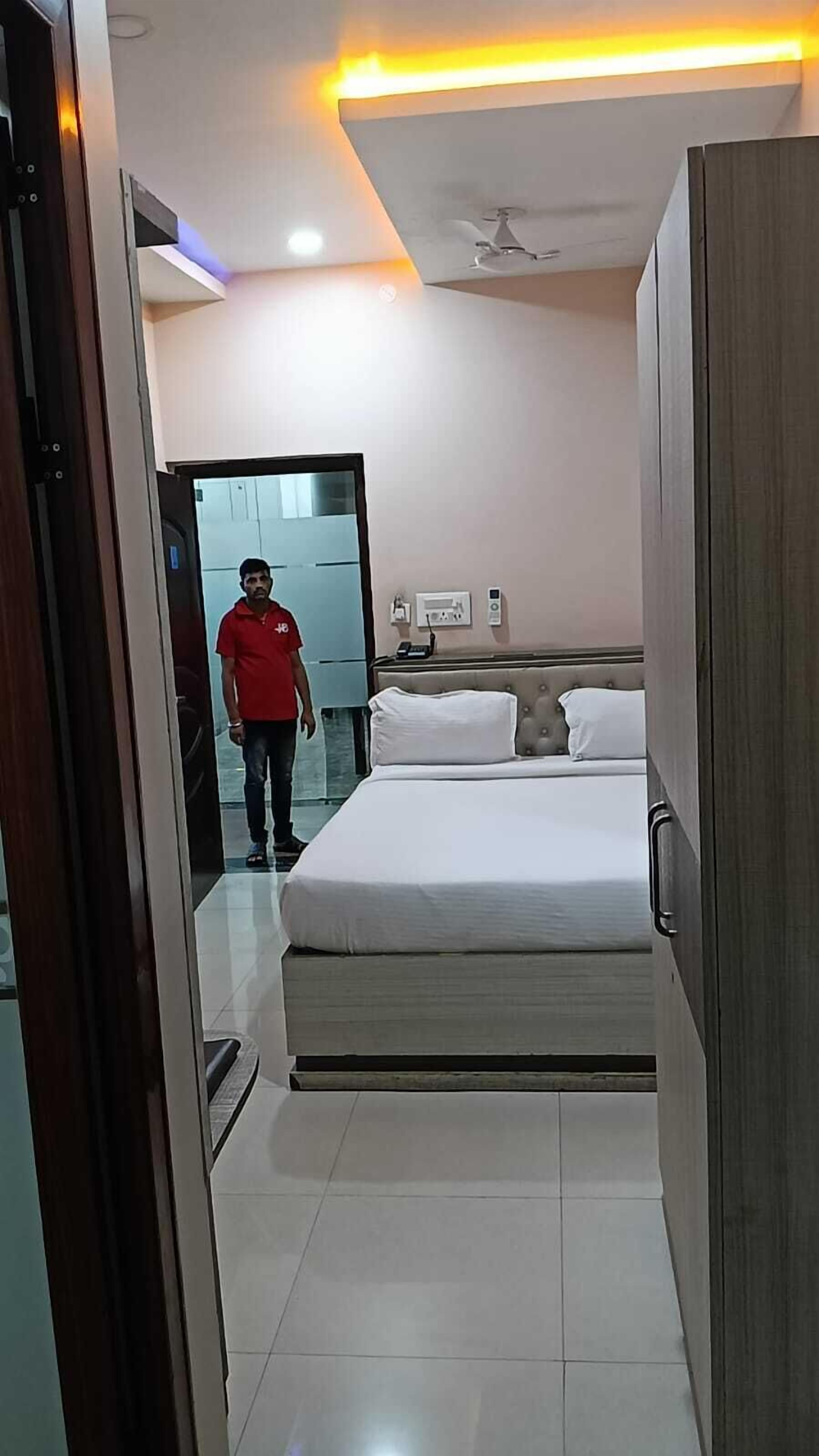 Una habitación de hotel con una cama, una mesita de noche, un teléfono en la pared y un ventilador de techo.