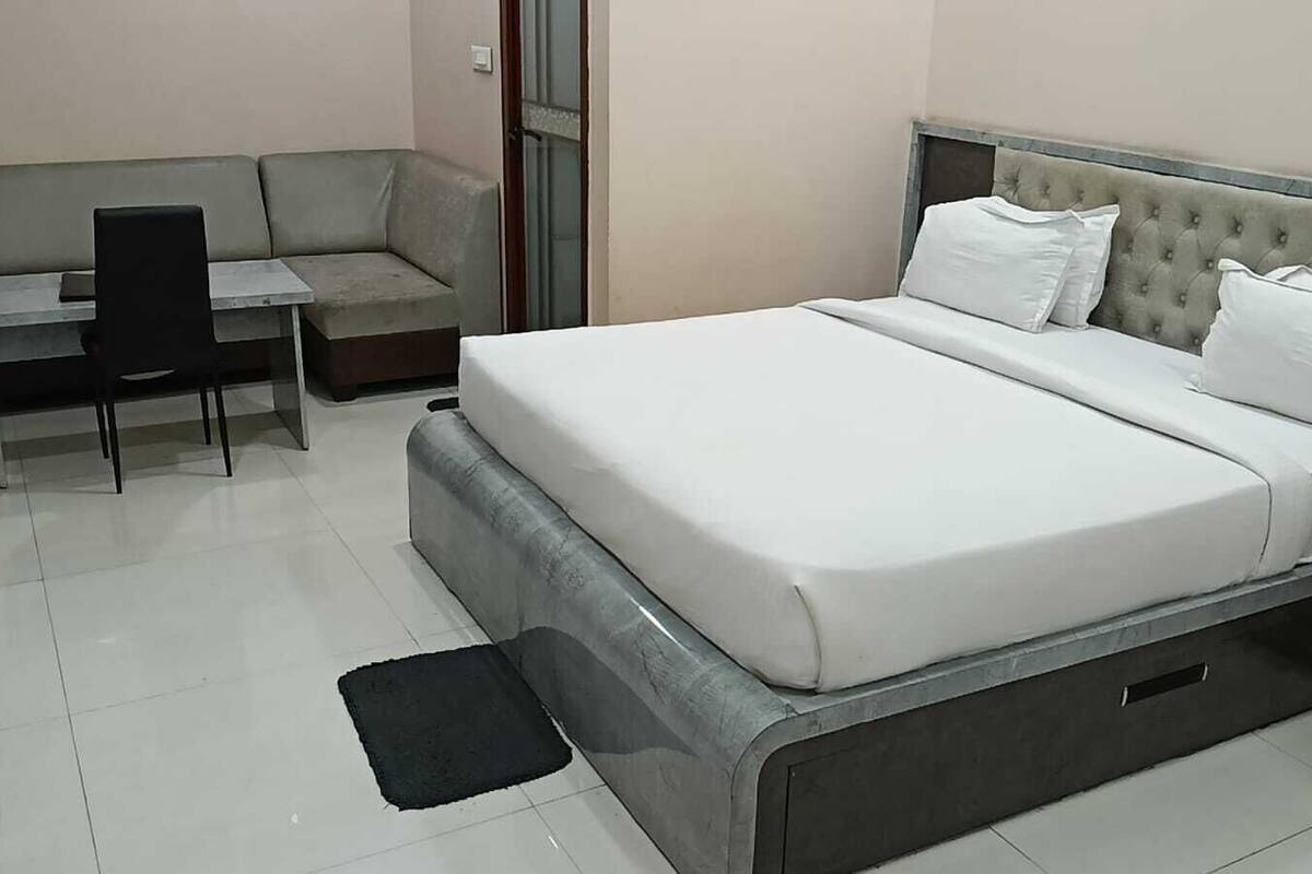 A neatly arranged bedroom with a bed, a desk, and a chair.