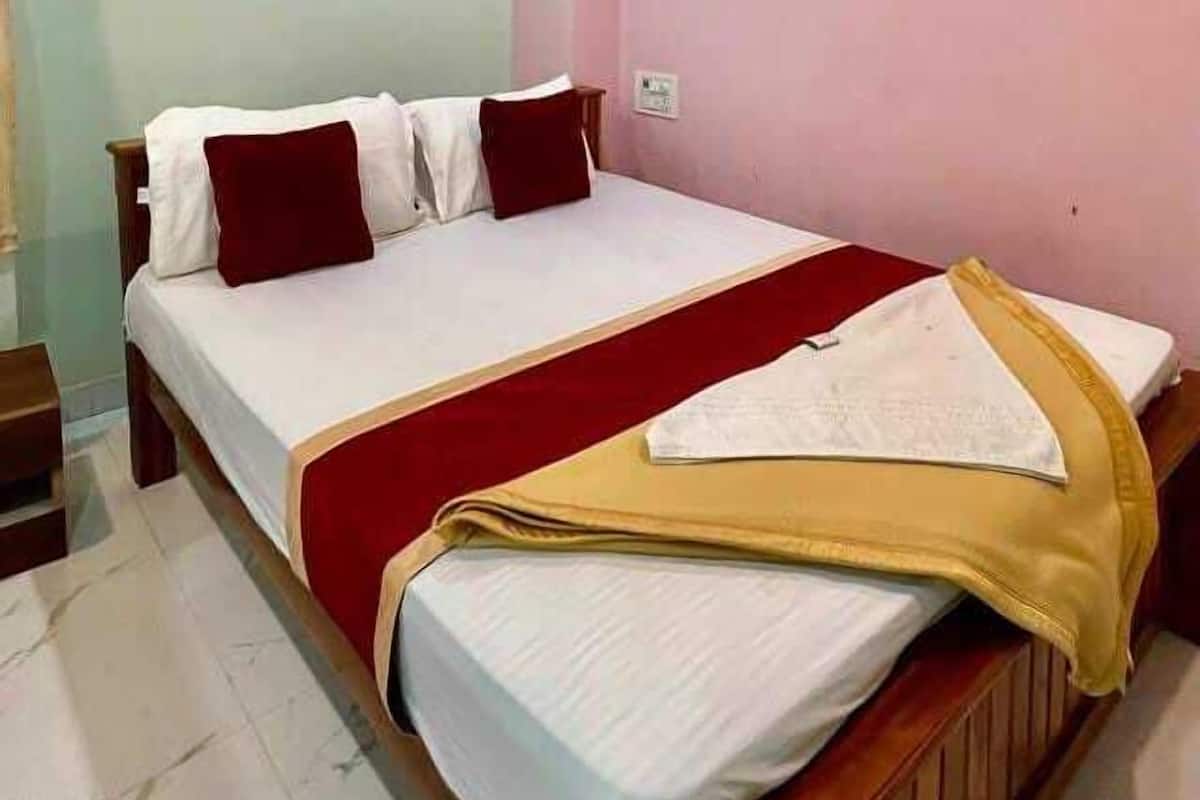 Un dormitorio con cama, almohadas, una mesita de noche y un ventilador de techo.