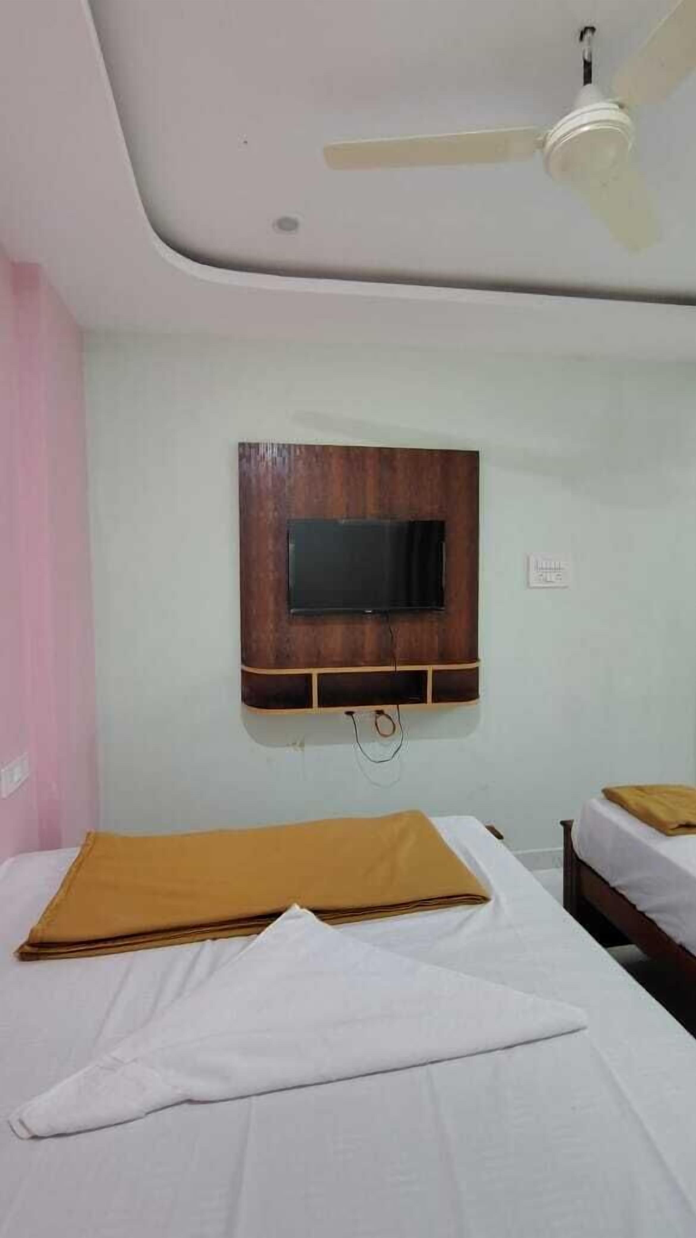 A bedroom with two beds, a ceiling fan, and a mounted TV.