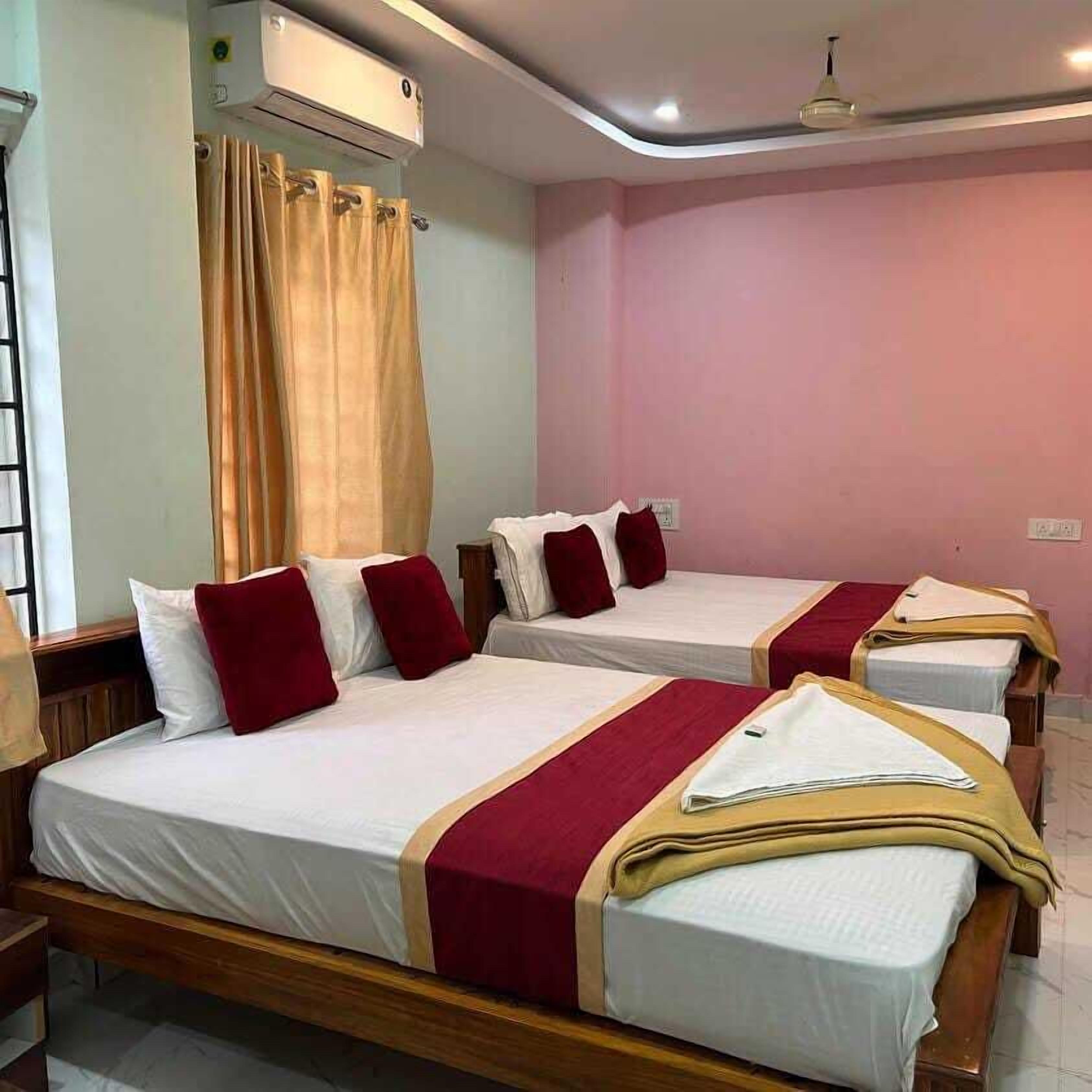 Habitación de hotel con dos camas individuales, cada una con cubrecama rojo y blanco, y cabeceros de madera.