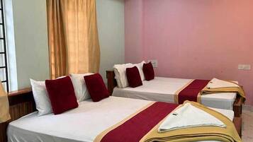 Habitación de hotel con dos camas individuales, cada una con cubrecama rojo y blanco, y cabeceros de madera.