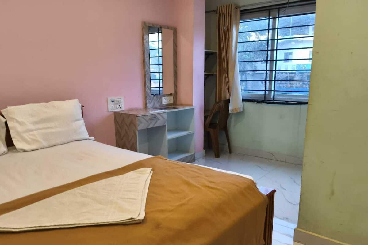 Un dormitorio con cama, escritorio, silla, ventana y espejo.