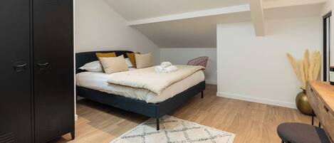 A bedroom with a bed, a desk, and a wardrobe.