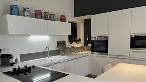A modern kitchen with white cabinetry, a Bosch oven, and a black induction cooktop.