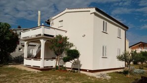 A two-story house with a covered porch, a chimney, and a small garden with a tree and shrubs. - Charming Apartments Dokoza Vir (Vir)