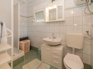 A bathroom with a toilet, sink, and a window above the mirror.