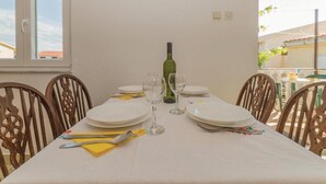 A dining table set with plates, cutlery, and a wine bottle, surrounded by wooden chairs. - Charming Apartments Dokoza Vir (Vir)