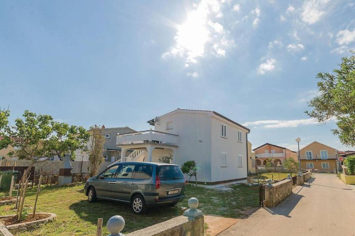 A residential area with a two-story house, a parked car, and a clear sky.