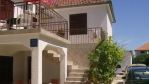 A two-story building with a balcony, a staircase, and a car parked in the driveway. - Charming Apartments Dokoza Drage (Pakostane)