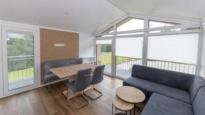 Een moderne, open woonruimte met een eethoek, bank en kleine tafeltjes.