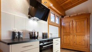 Une cuisine moderne avec un four noir, des armoires blanches et des portes en bois.