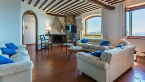 A spacious living room with a high ceiling, stone fireplace, and a view of the sea. - Stunning  villa for 10 people with A/C, WIFI, TV, patio and panoramic view (Castellina In Chianti)