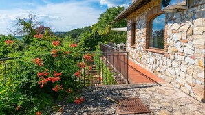 A stone building with a balcony overlooking a garden with red flowers. - Stunning  villa for 10 people with A/C, WIFI, TV, patio and panoramic view (Castellina In Chianti)