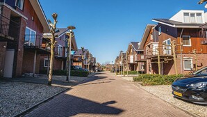 Una calle residencial con casas modernas, una vía pavimentada y coches aparcados.