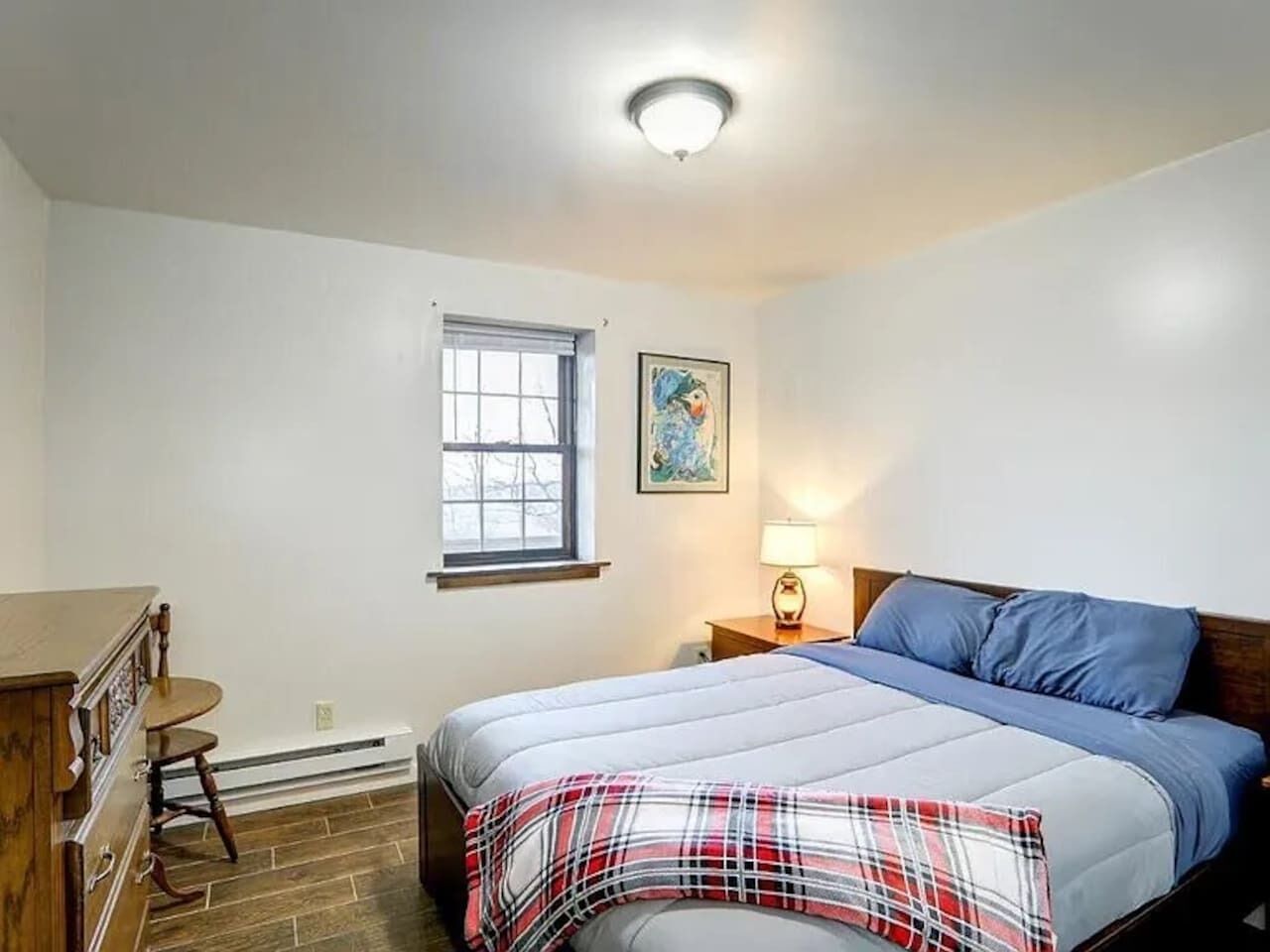 A bedroom with a bed, dresser, and window.