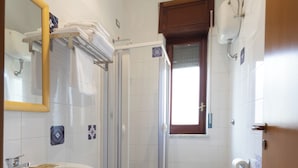 Un baño con lavamanos, bidé, inodoro y ducha con mampara de vidrio.