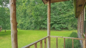 A wooden porch with a railing overlooking a grassy area with trees. - Lydia's Lodge in Pelham (Pelham)