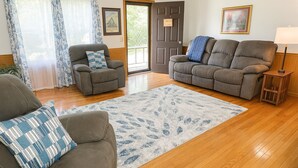 A living room with two sofas, a patterned rug, wooden flooring, a door, and a lamp. - Lydia's Lodge in Pelham (Pelham)