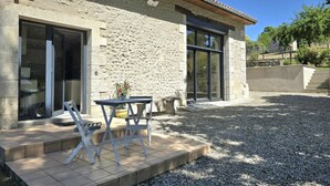 A stone building with a patio area, a table, and chairs. - Bright cottage with enclosed garden and parking (Comberanche-et-Épeluche)
