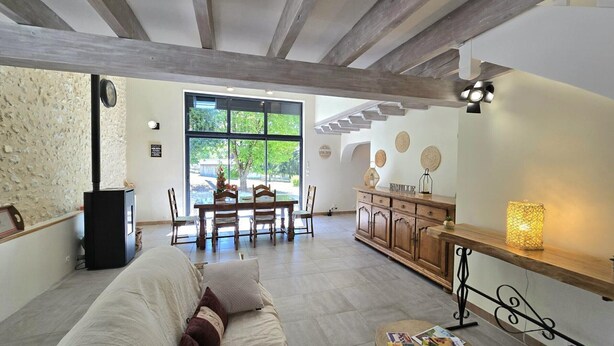 A spacious living room with a sofa, a dining table, and a kitchen area. - Bright cottage with enclosed garden and parking (Comberanche-et-Épeluche)