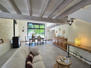 A spacious living room with a sofa, a dining table, and a kitchen area. - Bright cottage with enclosed garden and parking (Comberanche-et-Épeluche)