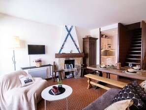 Una sala de estar acogedora con chimenea, un comedor y una cocina visible a través de una puerta abierta.