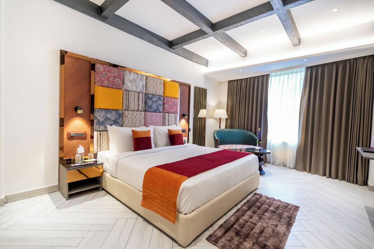 Een moderne hotelkamer met een groot bed, een nachtkastje, een bureau en uitzicht op de omgeving.