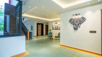 Un moderno vestíbulo de hotel con una escalera, un mostrador de recepción y una obra de arte de un elefante en la pared.