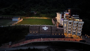 Un hôtel avec une grande enseigne portant le nom « Crescento », fixée à un mur de pierre, entouré d’un parking bien éclairé et d’un champ d’herbe.