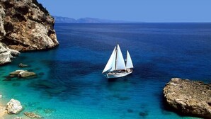 A sailboat on a clear blue sea with rocky shores. - LOCANDA SU RECREU (Cala Gonone)