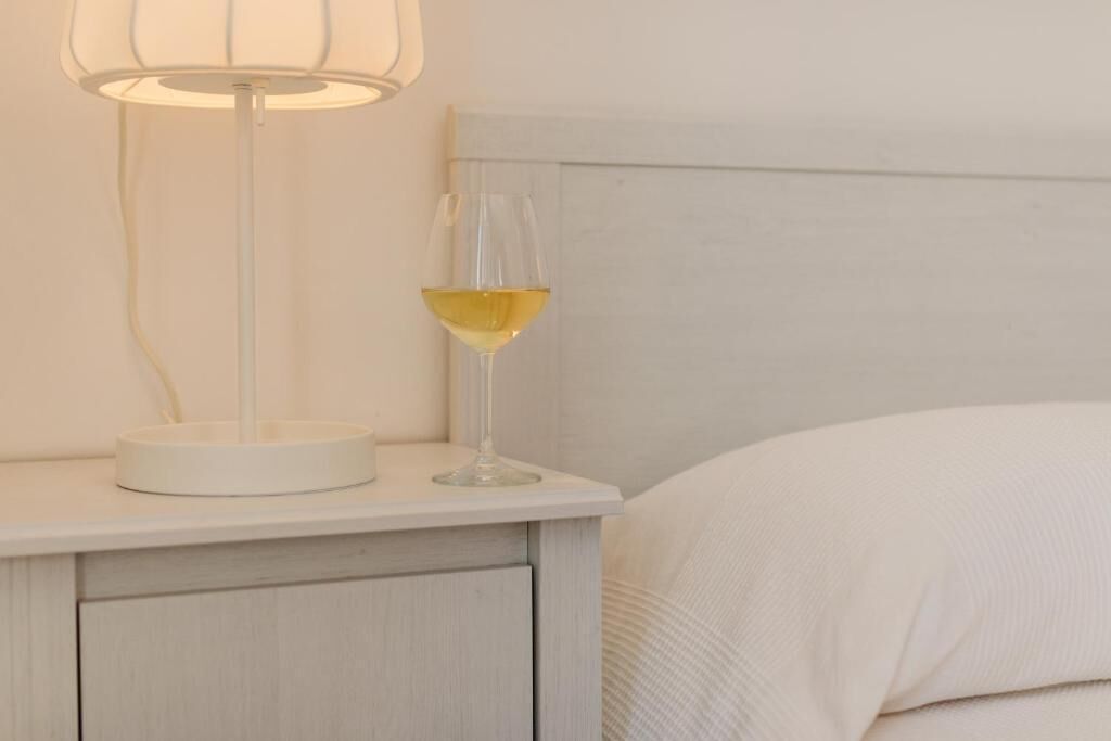 Un comodino con una lampada e un bicchiere di vino.