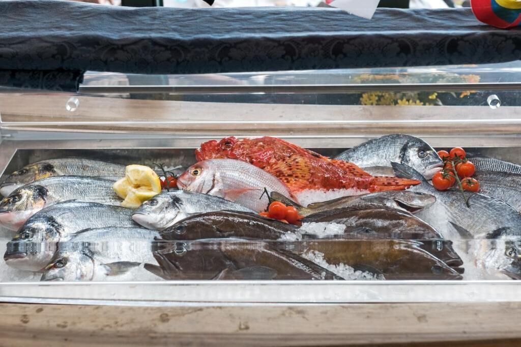 A display of various fish on ice with some garnishes.