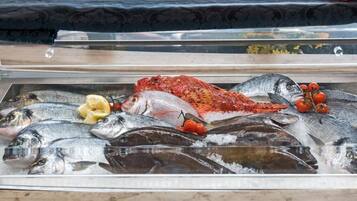 A display of various fish on ice with some garnishes.