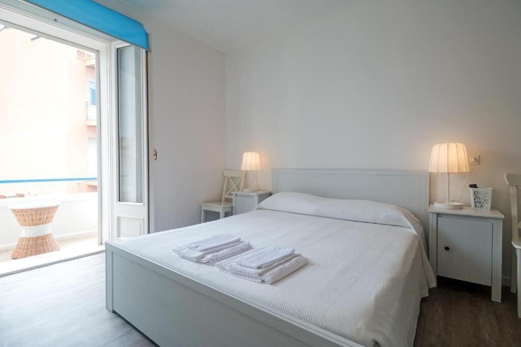 A hotel room with a bed, two bedside tables, a lamp, and a view through a sliding door.