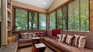A cozy living room with a brown sofa, patterned cushions, a wooden coffee table, and a large window with blinds. - Dobie 36  with Wintergreen Advantage (Wintergreen)