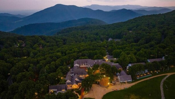 An aerial view of a residential area with multiple houses surrounded by dense forest, featuring a central building with a prominent roof and a well-lit driveway. - Dobie 36  with Wintergreen Advantage (Wintergreen)