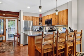 A modern kitchen with wooden cabinets, stainless steel appliances, and a central island with seating. - Dobie 48  with Wintergreen Advantage (Wintergreen)